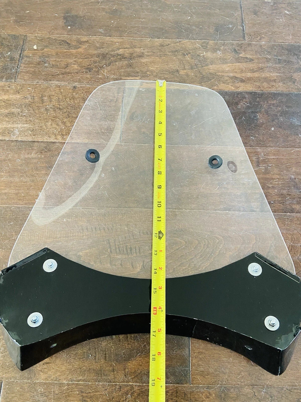Metal bracket with a measuring tape for scale on a wooden floor
